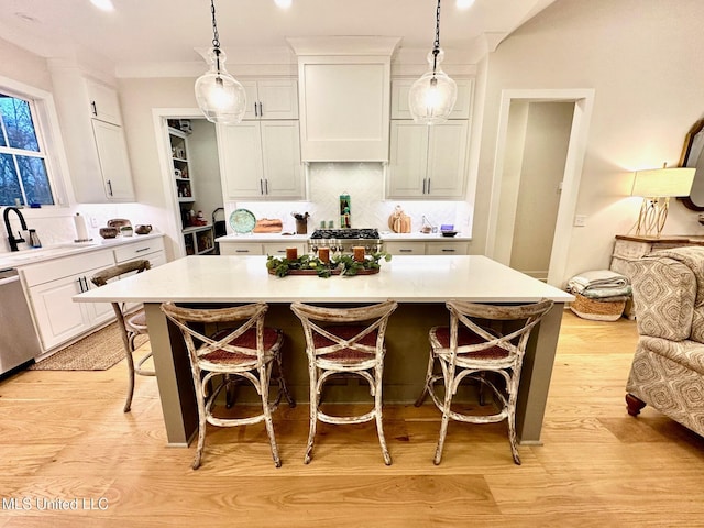 kitchen featuring white cabinetry, a center island, hanging light fixtures, a kitchen breakfast bar, and stove