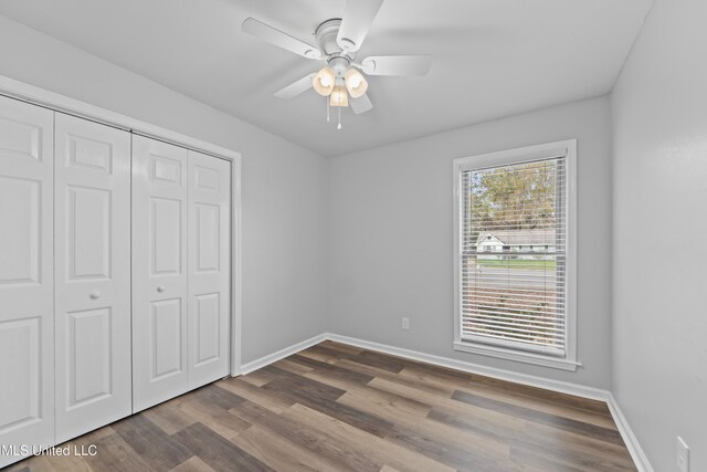 unfurnished bedroom with ceiling fan, a closet, and dark wood-type flooring