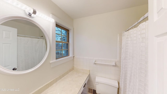 bathroom with tile walls, vanity, and toilet