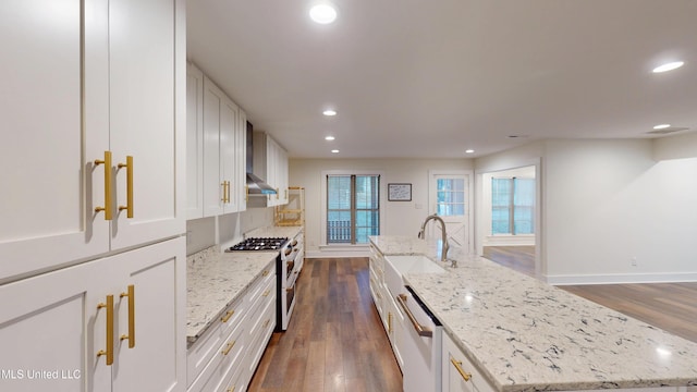 kitchen featuring light stone counters, stainless steel appliances, a kitchen island with sink, and white cabinets