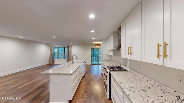 kitchen with high end white range oven, an island with sink, and white cabinets