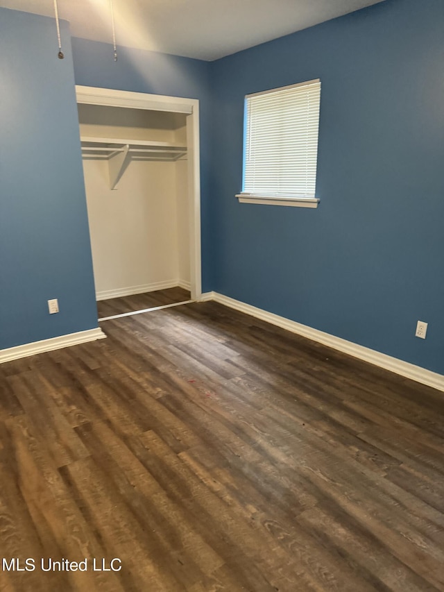 unfurnished bedroom featuring a closet and dark hardwood / wood-style flooring