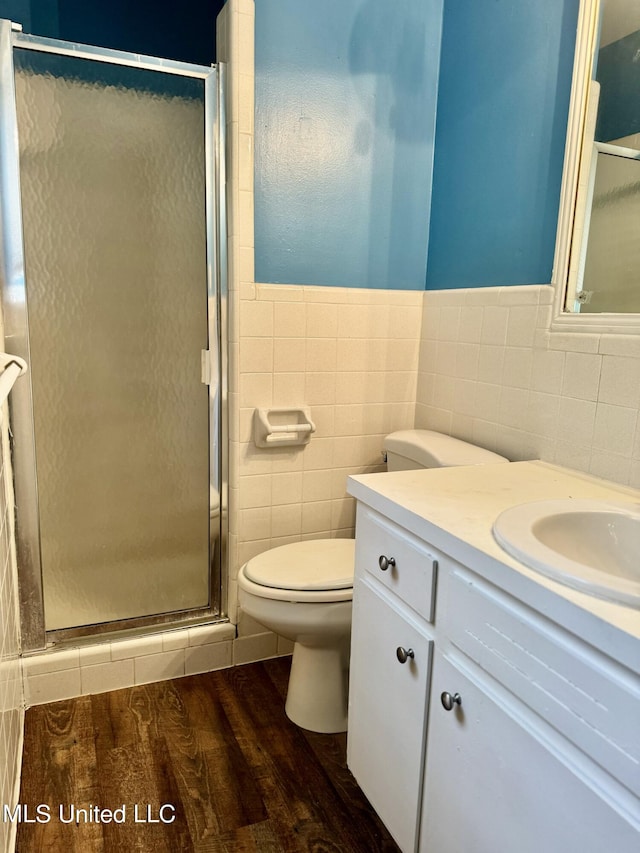 bathroom featuring tile walls, vanity, wood-type flooring, and walk in shower