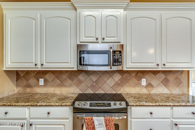 kitchen featuring light stone countertops, white cabinetry, appliances with stainless steel finishes, and tasteful backsplash