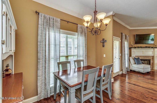 dining area featuring dark hardwood / wood-style flooring, an inviting chandelier, a tile fireplace, and crown molding