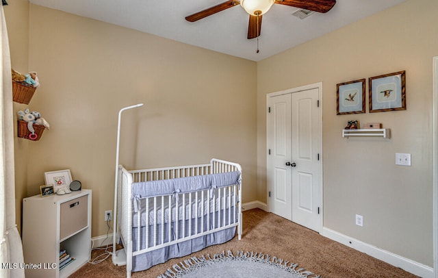 carpeted bedroom with a closet, a nursery area, and ceiling fan