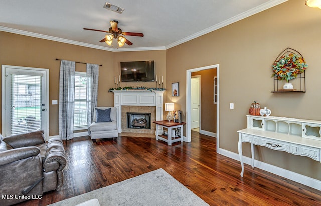 living room with ornamental molding, ceiling fan, a tile fireplace, and dark hardwood / wood-style floors