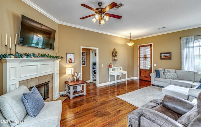 living room featuring dark hardwood / wood-style flooring, ceiling fan, ornamental molding, and a fireplace