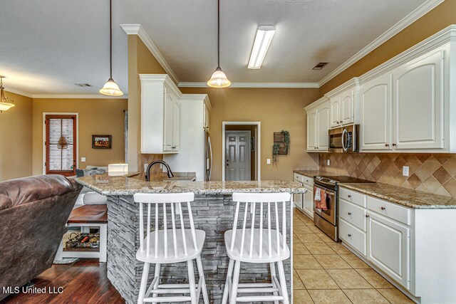 kitchen with white cabinets, stainless steel appliances, hanging light fixtures, and light stone counters