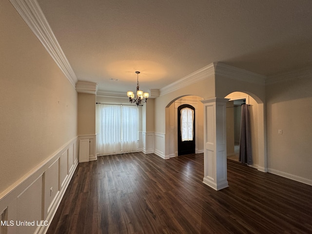 unfurnished room featuring dark hardwood / wood-style flooring, a notable chandelier, decorative columns, a textured ceiling, and ornamental molding