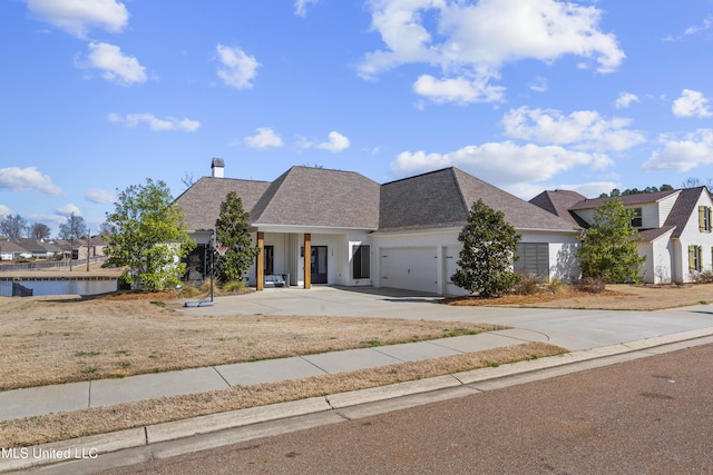 view of front facade featuring a garage, concrete driveway, a water view, and stucco siding