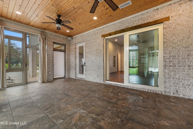 interior space with ceiling fan, wood ceiling, and brick wall