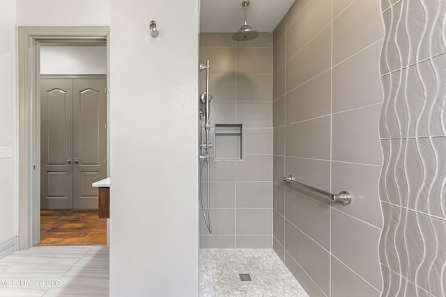 bathroom featuring wood-type flooring, vanity, and a tile shower