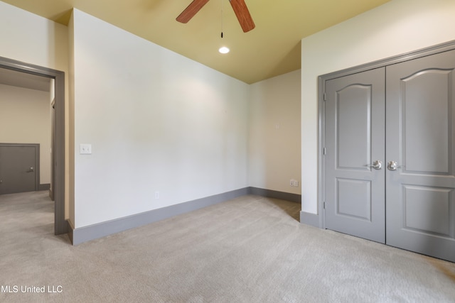 unfurnished bedroom featuring ceiling fan, light colored carpet, and a closet