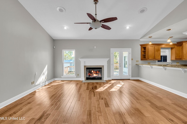 unfurnished living room with light hardwood / wood-style floors, vaulted ceiling, ceiling fan, and french doors