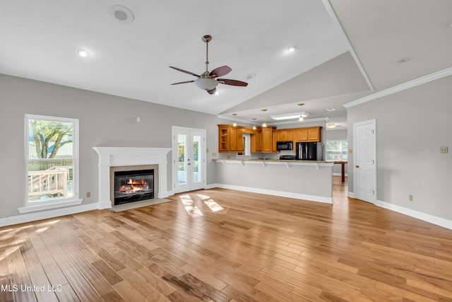 unfurnished living room with light hardwood / wood-style floors, high vaulted ceiling, ceiling fan, and french doors