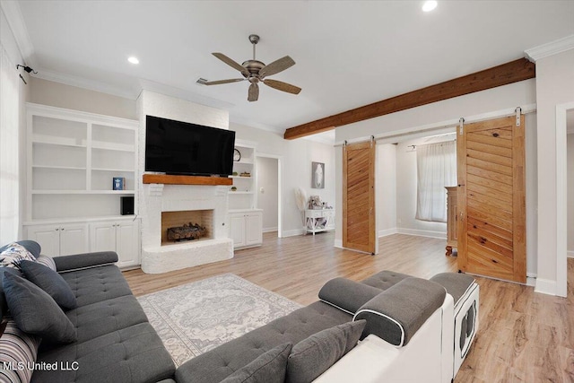 living room featuring crown molding, a barn door, light wood-type flooring, and ceiling fan