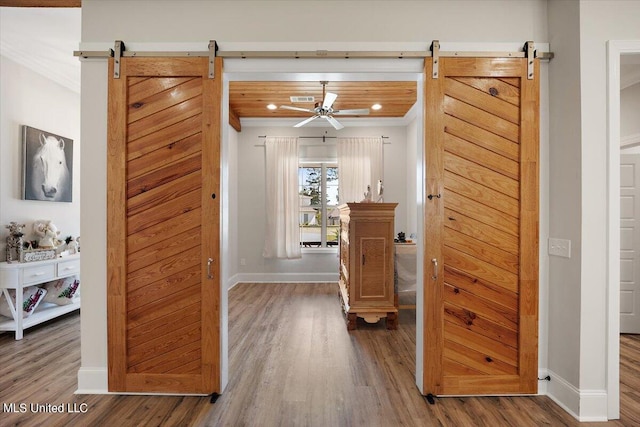 hallway featuring wood ceiling, ornamental molding, a barn door, and hardwood / wood-style floors