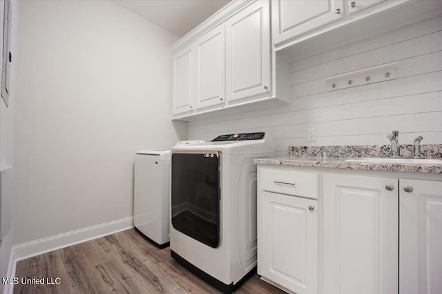 laundry area featuring sink, washer and dryer, light wood-type flooring, and cabinets