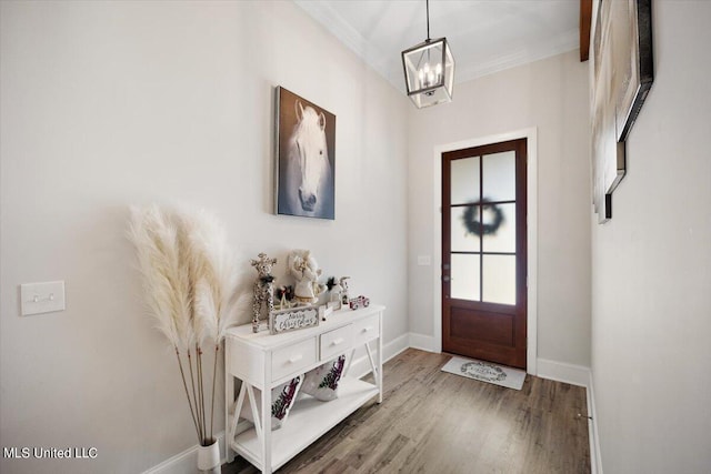 entrance foyer with ornamental molding, an inviting chandelier, and hardwood / wood-style floors