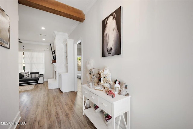 hallway with beamed ceiling, crown molding, and light hardwood / wood-style flooring