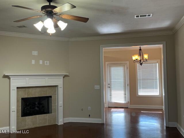 708 Bo Blaze Cv, Brandon, MS 39047 - unfurnished living room featuring crown molding, dark wood-type flooring, baseboards, a chandelier, and a tiled fireplace