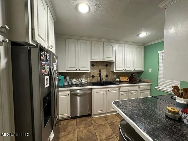 133 Windchase, Brandon, MS 39042 - kitchen featuring appliances with stainless steel finishes, white cabinets, backsplash, dark tile patterned floors, and crown molding