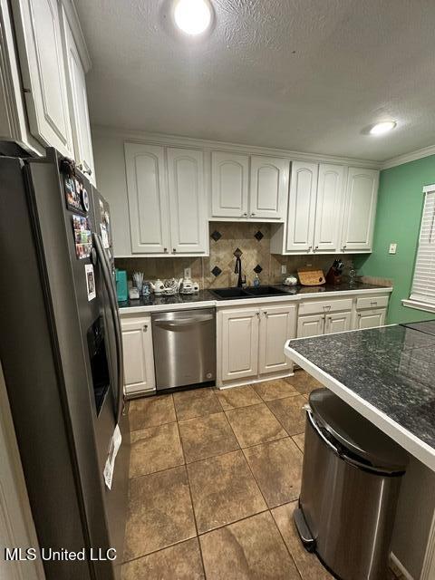 133 Windchase, Brandon, MS 39042 - kitchen featuring appliances with stainless steel finishes, white cabinets, dark tile patterned flooring, dark countertops, and a textured ceiling