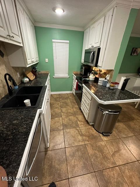 133 Windchase, Brandon, MS 39042 - kitchen with appliances with stainless steel finishes, crown molding, dark countertops, white cabinets, and dark tile patterned flooring