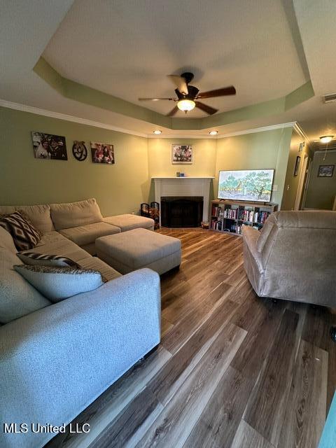 133 Windchase, Brandon, MS 39042 - living room featuring a raised ceiling, ceiling fan, dark wood-type flooring, a fireplace, and crown molding