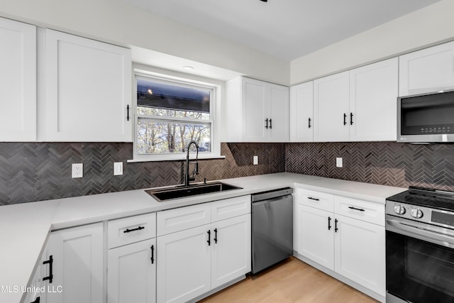 kitchen with tasteful backsplash, appliances with stainless steel finishes, light countertops, and a sink