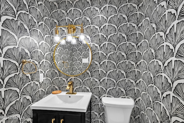 bathroom with toilet, wallpapered walls, and vanity