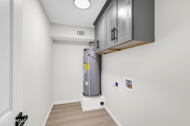 laundry room with hookup for a washing machine, visible vents, water heater, cabinet space, and light wood finished floors