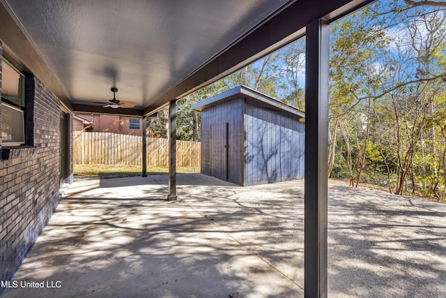 view of patio with a storage unit, an outdoor structure, fence, and a ceiling fan