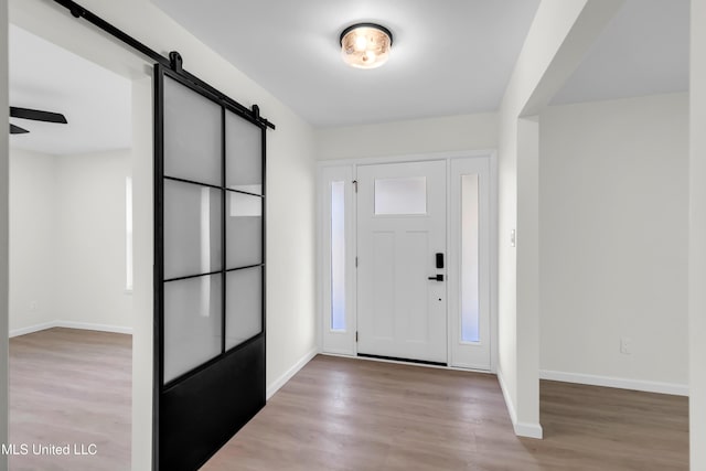 foyer featuring a barn door, wood finished floors, and baseboards