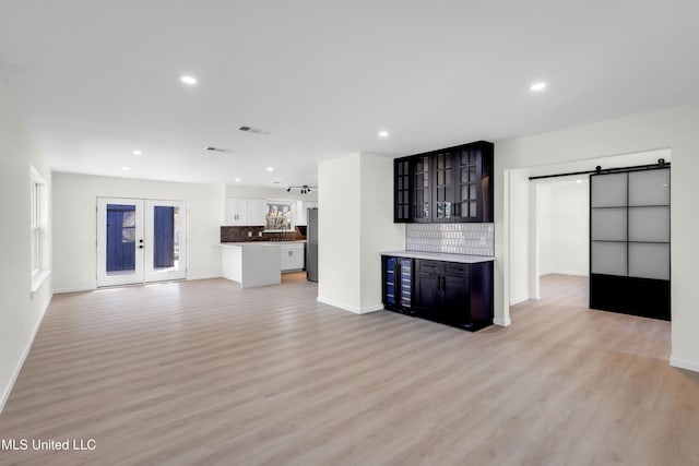 unfurnished living room with a barn door, light wood-style flooring, and recessed lighting