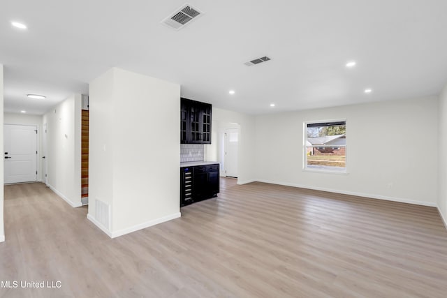 unfurnished living room featuring visible vents, light wood-style flooring, and stairs