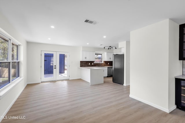 kitchen with a sink, visible vents, white cabinets, french doors, and fridge