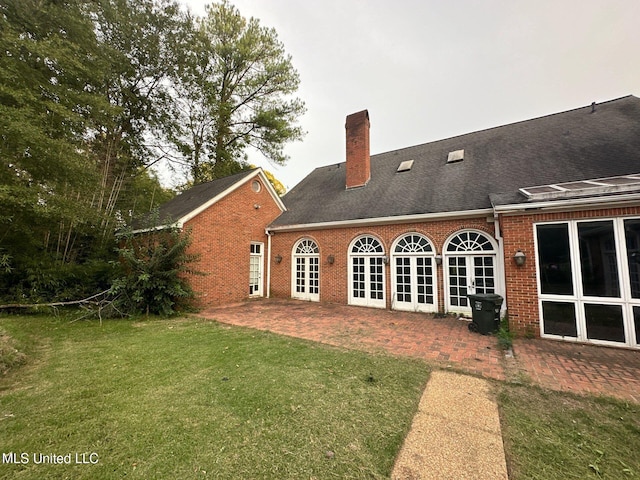 rear view of house featuring a patio, a lawn, and french doors