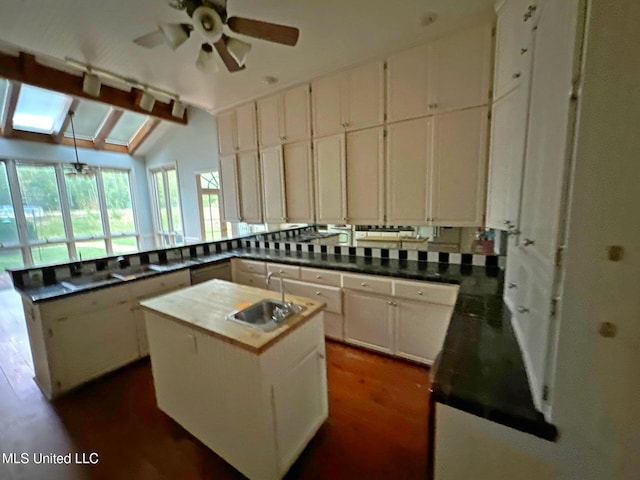 1912 N Petit Bois St, Jackson, MS 39211 - kitchen with lofted ceiling with skylight, a sink, white cabinets, a kitchen island with sink, and ceiling fan