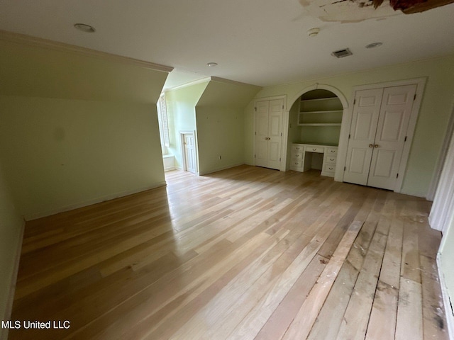 bonus room with built in shelves, vaulted ceiling, built in desk, and light hardwood / wood-style flooring