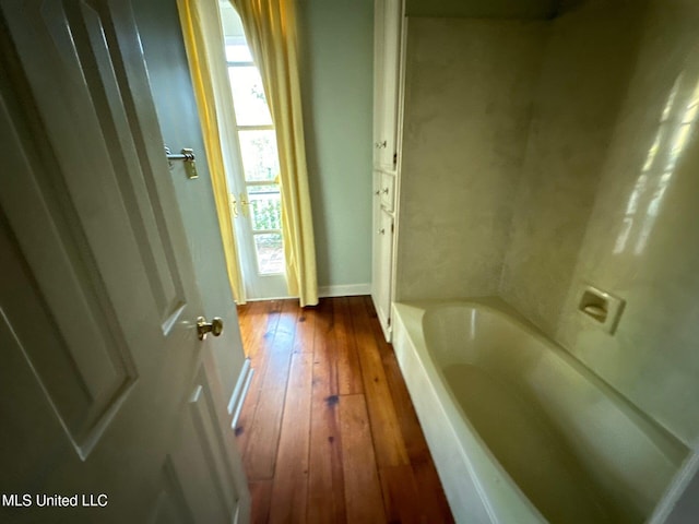 bathroom with hardwood / wood-style floors and a bath