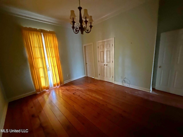 unfurnished room featuring hardwood / wood-style floors, a notable chandelier, and crown molding