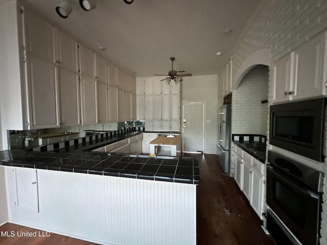 1912 N Petit Bois St, Jackson, MS 39211 - kitchen featuring a peninsula, tile countertops, black appliances, dark wood-style flooring, and ceiling fan