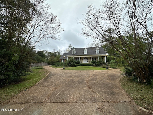 new england style home with a front yard and covered porch