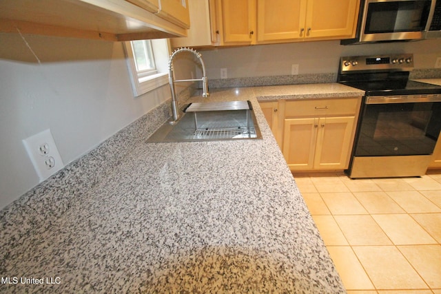 kitchen with a sink, light countertops, light tile patterned floors, and stainless steel appliances