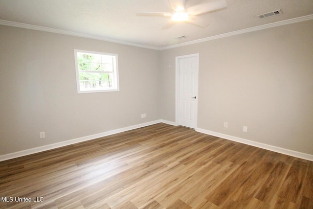 spare room with crown molding, ceiling fan, wood finished floors, and visible vents