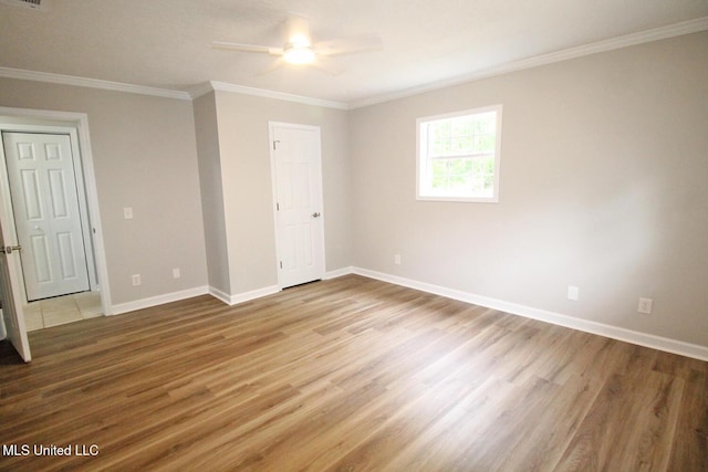 unfurnished bedroom featuring a ceiling fan, visible vents, wood finished floors, baseboards, and ornamental molding