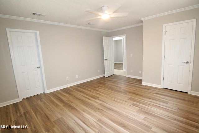 unfurnished bedroom featuring baseboards, ornamental molding, light wood finished floors, and visible vents