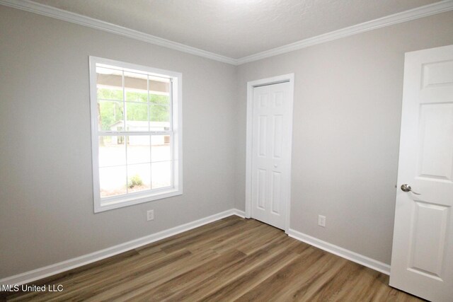 unfurnished bedroom with crown molding, baseboards, a closet, and wood finished floors